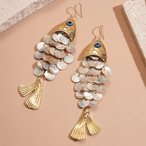 Close-up of golden fish earrings with iridescent shell scales and blue evil eye detail