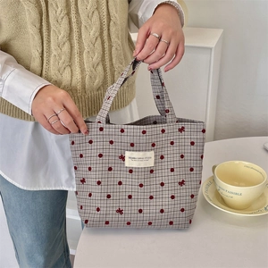 Vue détaillée du sac à lunch en toile à carreaux avec broderie de nœud rouge à la main