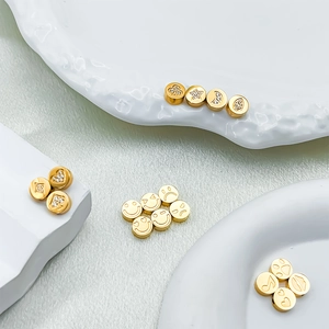 Dettaglio macro di perle rotonde placcate in oro 14k con motivi incisi e zirconi