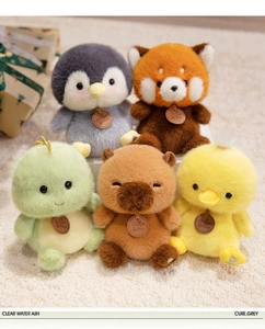 Close-up of fluffy penguin, panda, and capybara plush toys with leather tags on soft carpet