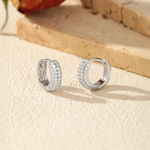 Boucles d'oreilles créoles en argent S925 avec pierres moissanites pavées sur fond beige