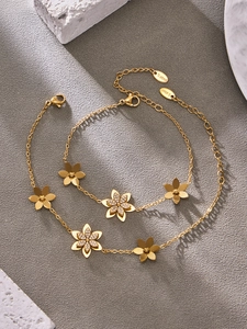 Dettaglio di due bracciali a fiore in acciaio inossidabile dorato con zirconi lucenti