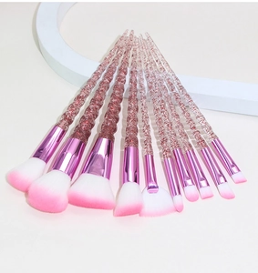 Close-up of unicorn makeup brushes with spiral glitter handles and pink gradient bristles