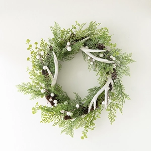 Christmas wreath with white antlers pine cones and green cedar foliage on white background