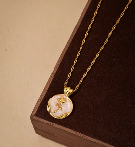 Detailed close-up of a gold rose relief pendant necklace on a vintage wooden box