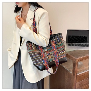 Ethnic tote bag with colorful geometric patterns and black leather base worn by a model