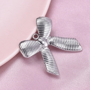Close-up of silver 304 stainless steel bow pendant on pink silk background