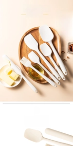Overhead view of a 6-piece white silicone spatula set on a wooden tray with baking ingredients