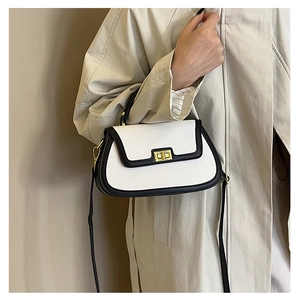 Détail d'un sac à main en cuir blanc avec bordure noire et fermoir rotatif doré élégant