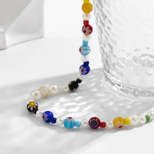 Detailed close-up of colorful glass flower beads and pearls on a white surface