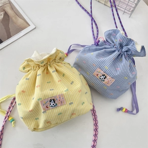 Detail of gingham drawstring pouches in yellow and blue with cartoon cow labels
