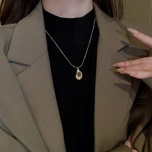 Detail view of a vintage gold necklace featuring a teardrop brown tiger eye stone