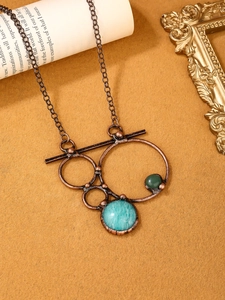 Detailed close-up of vintage bronze geometric pendant necklace with natural stone stones