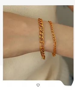 Detailed close-up of gold Figaro chain bracelets on wrist with elegant polished finish