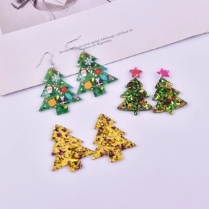 Close-up of DIY acrylic Christmas tree earrings with green prints and gold glitter finish