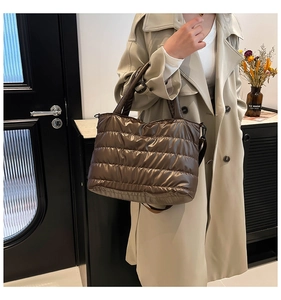 Detail of deep brown quilted puffer tote bag featuring glossy texture and versatile straps