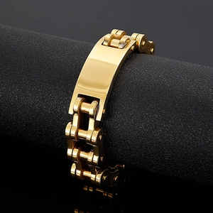 Detail of a gold motorcycle chain bracelet for men displayed on a black textured stand