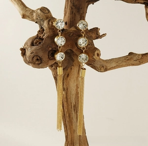 Détail de boucles d'oreilles à pampilles avec trois zircons ronds en acier plaqué or 18 carats