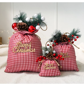 Three sizes of red buffalo plaid Christmas gift bags with pine cones and berries