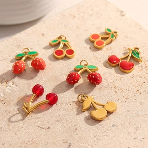 Detailed macro view of red enamel and 18K gold cherry pendants for DIY jewelry