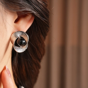 Close-up of model wearing silver twisted textured earring with a large black bead accent