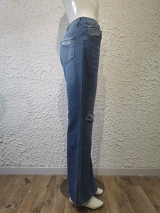 Gros plan des déchirures stylées sur le côté du jean évasé bleu en denim délavé