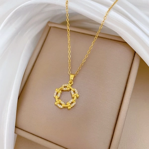 Close-up of golden spinning ring necklace with zircon pavé on white silk background
