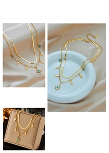 Detail of layered gold titanium necklace with turquoise evil eye and lightning charms