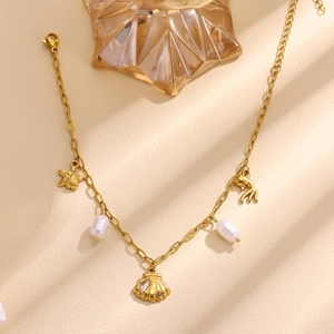 Detail of gold starfish and shell pendant necklace with pearls on beige leather background