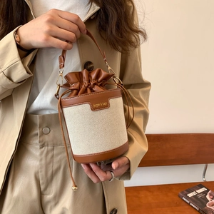 Minimalist canvas and brown leather bucket bag with drawstring closure for women