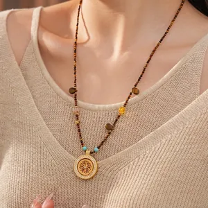 Tiger eye beaded long necklace with gold mandala flower pendant worn by a model