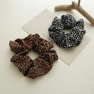 Pair of vintage leopard print scrunchies in brown and black on a minimalist background