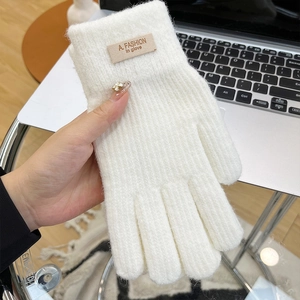 Close-up of white knitted winter glove with a fashion patch and thick warm texture