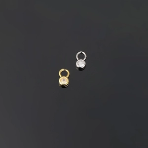 Detailed view of gold and silver round pendants with inlaid sparkling zircon stones