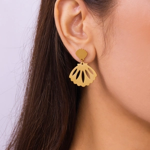 Close-up of gold shell earrings with hollow flower detail on model with soft lighting