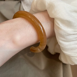 Macro detail of amber resin cuff bracelet with marble texture on woman's wrist