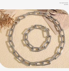 Detail of silver heavy chunky U-link chain necklace and bracelet jewelry set on textured base
