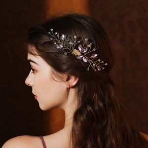 Dettaglio di pettine per capelli con fiori di cristallo viola e foglie dorate
