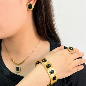 Dettaglio di modella che indossa set di gioielli dorati con pietre nere ovali e finitura