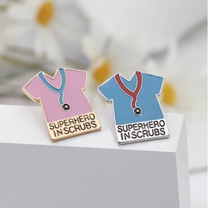Macro shot of two medical enamel pins with Superhero in Scrubs text and stethoscopes