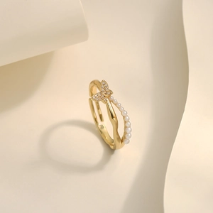 Detailed view of adjustable golden ring with sparkling butterfly and pearl accents