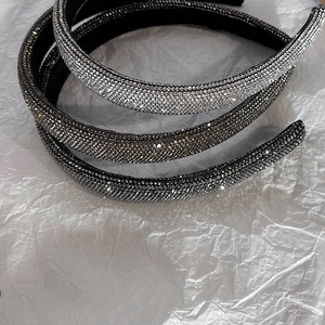 Dettaglio di un cerchietto di lusso con strass brillanti su carta bianca minimalista