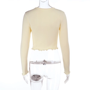 Detail of lettuce edge hem and ribbed knit texture on light yellow long sleeve crop top