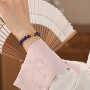 Close-up of a purple amethyst beaded bracelet with a gold bead on a model's wrist