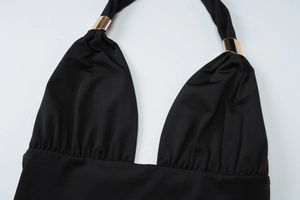 Close-up of black halter neck knit top with golden metallic buckle detail