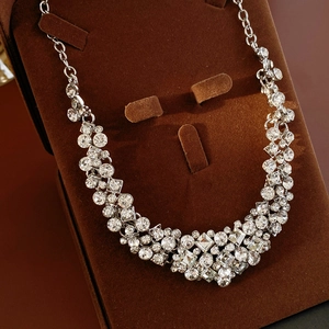 Close-up of geometric diamond-set necklace on a brown velvet jewelry display stand