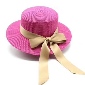 Dettaglio del cappello di paglia rosa con elegante nastro di raso color champagne