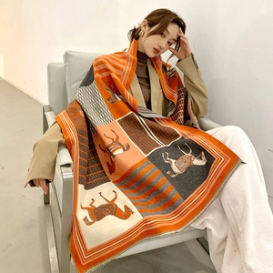 Detailed view of scarf featuring horse patterns and geometric textures in orange and grey