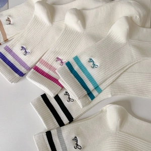 Detailed close-up of white cotton socks with colorful double stripes and Smile embroidery
