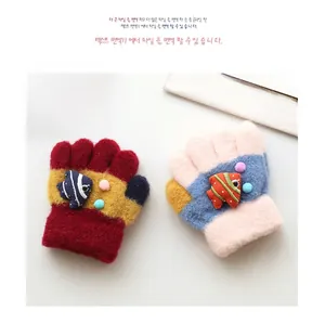 Detail of knit children's gloves with colorful拼接 fish charms and soft fuzzy pom poms